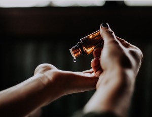 A massage therapist pouring oil into their hands