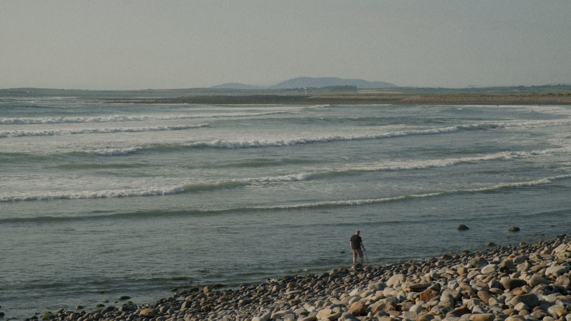 A man walks along the shore