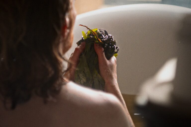 A person holding seaweed in a bathtub