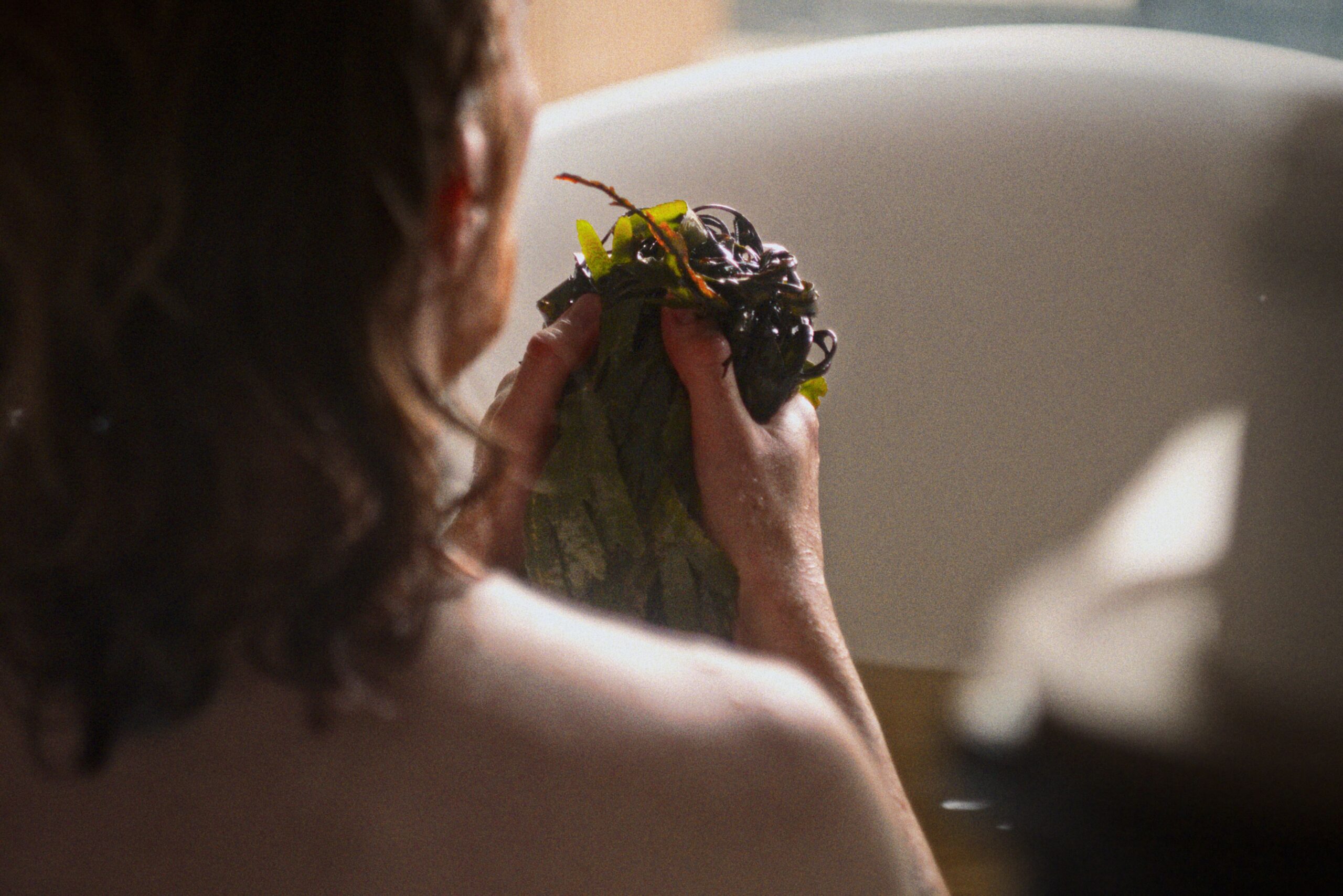 A person holding seaweed in a bathtub